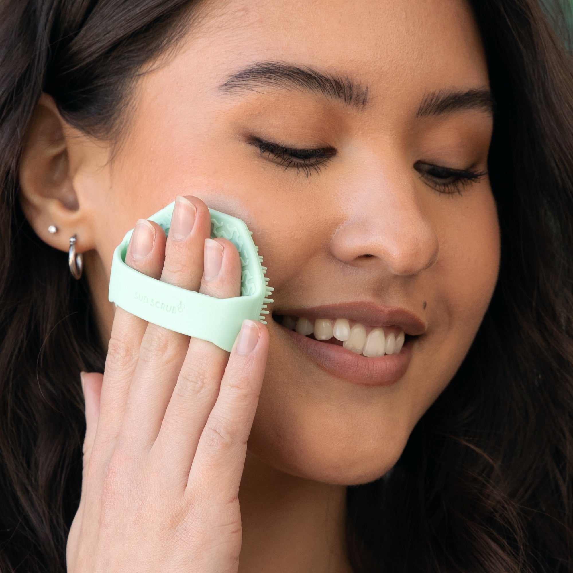 woman using Sud Scrub Face Scrubber on her face