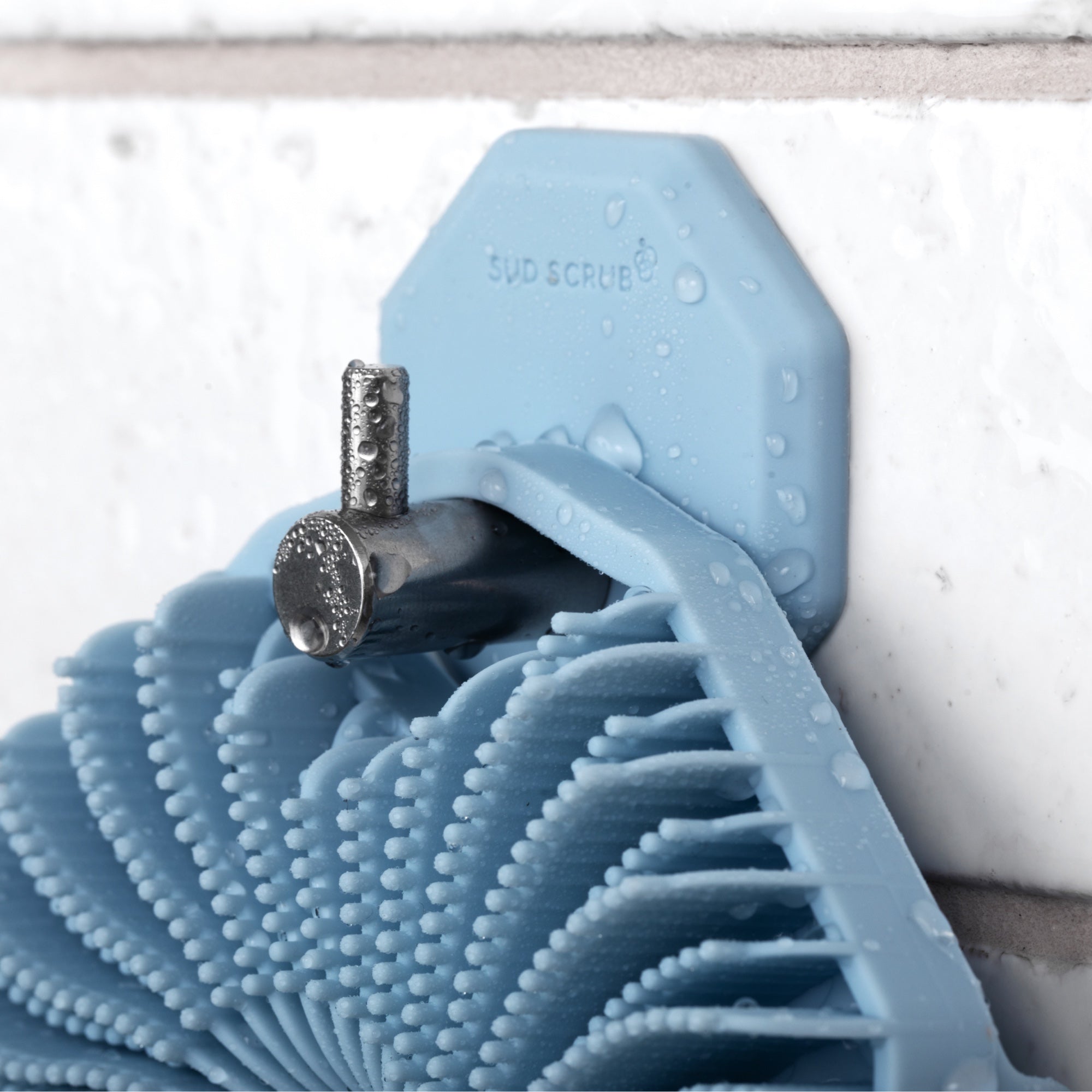Up close detailed shot of Blue Sud Scrub Body Scrubber hanging on the Blue Sud Scrub Shower Hook in the shower.