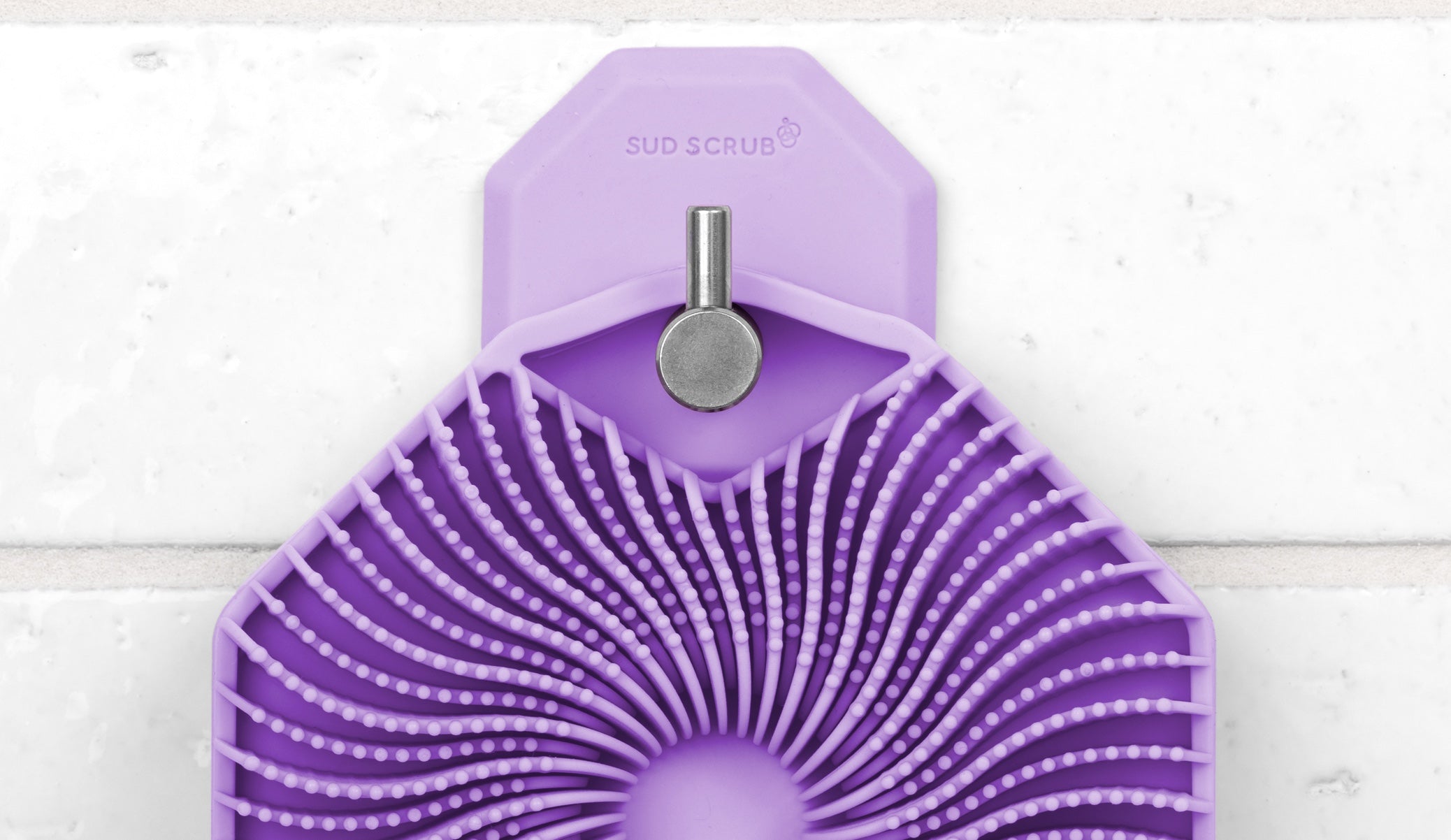 Close up shot of the purple Sud Scrub Body Scrubber hanging on the purple Sud Scrub Shower Hook