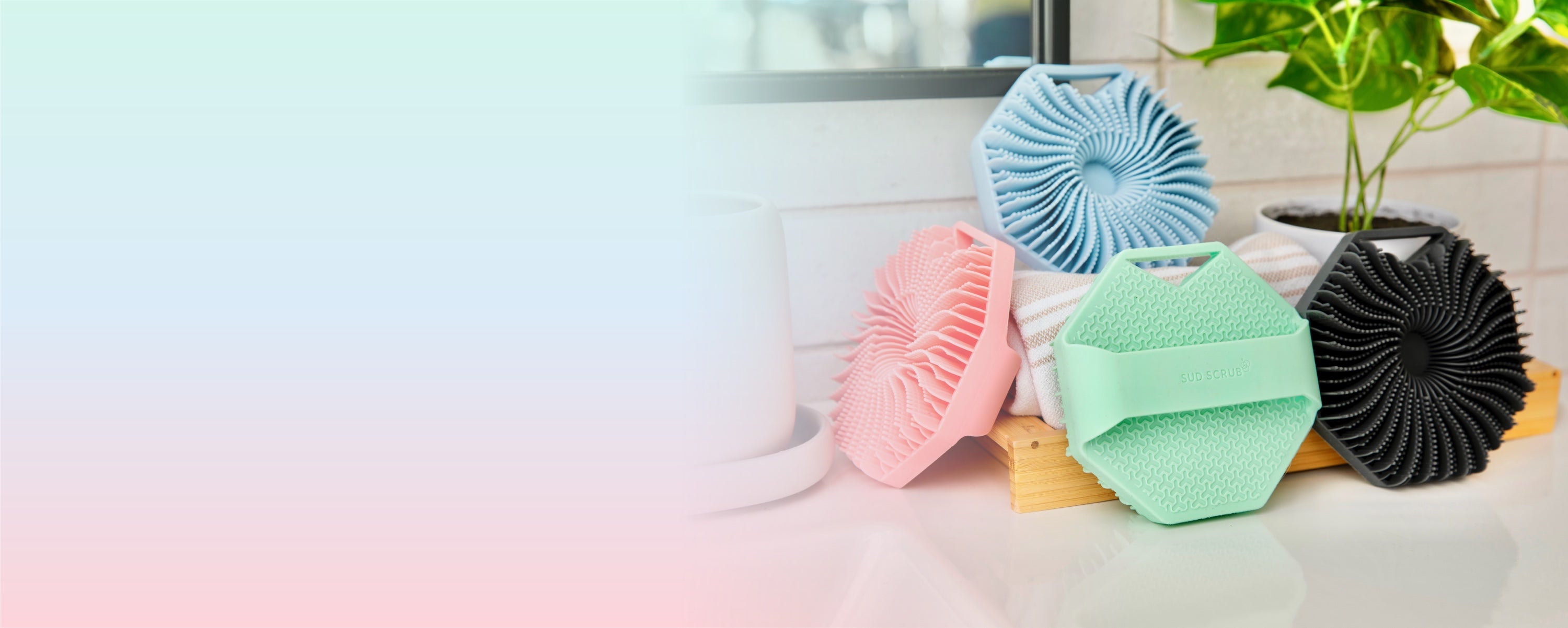 multiple colors of Sud Scrub Body Scrubbers, piled up onto each other in a bathroom setting.