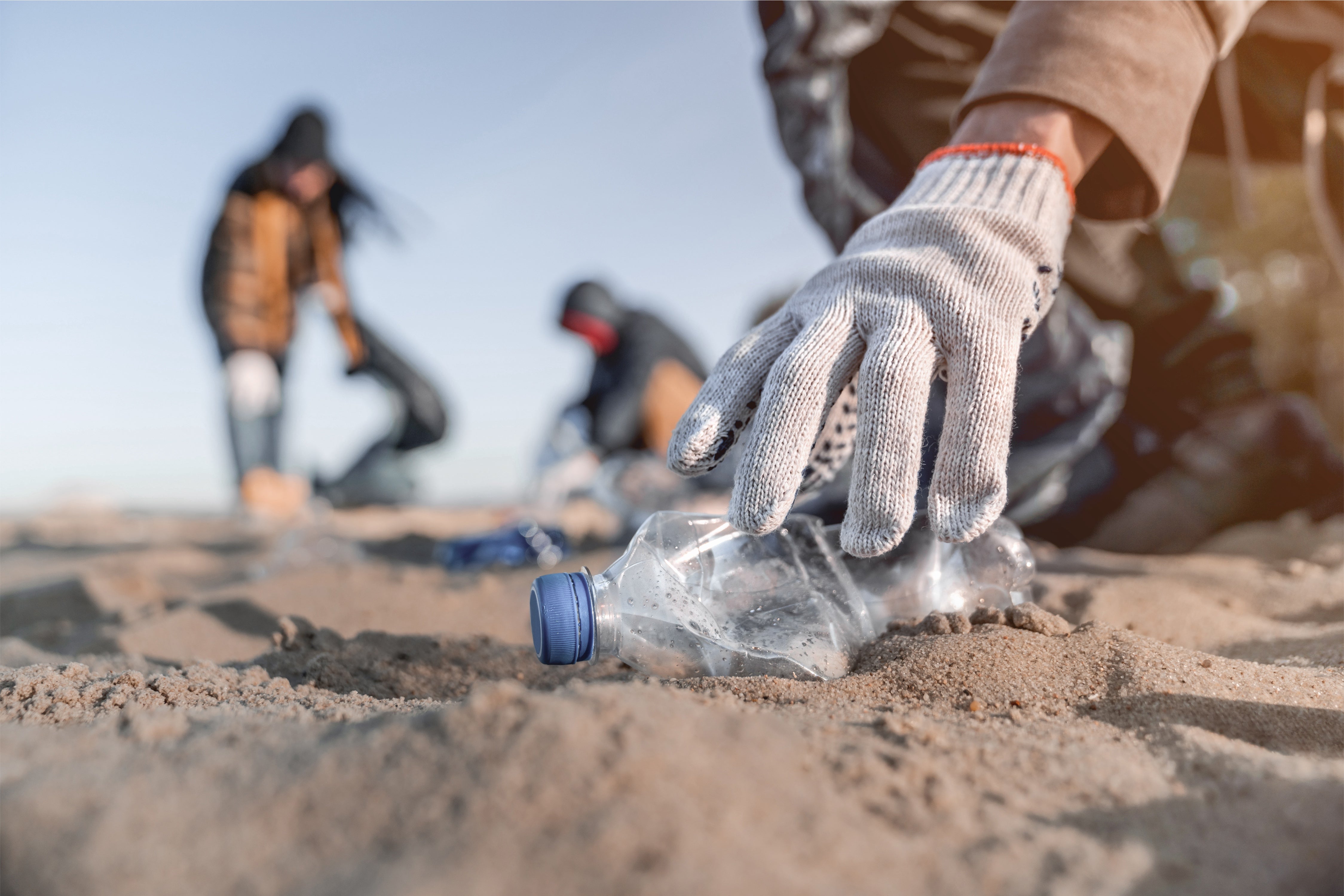 hand picking up trash on the beach