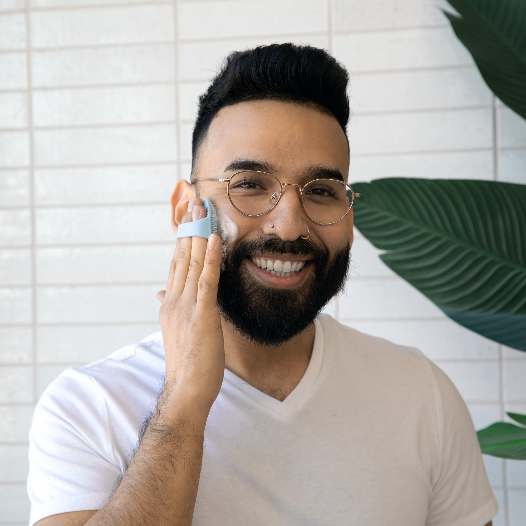 man using Sud Scrub face scrubber on his face in the bathroom