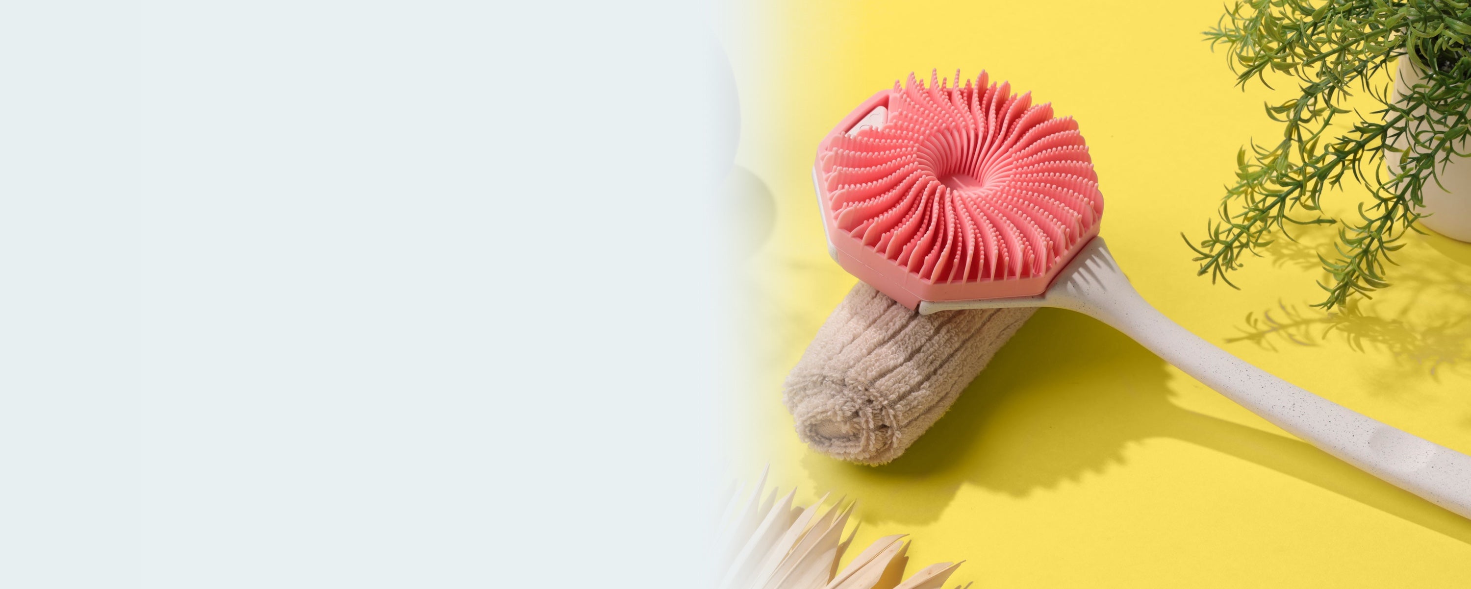 Pink Sud Scrub Body Scrubber fastened onto the Sud Scrub Extender Handle ina bathroom setting