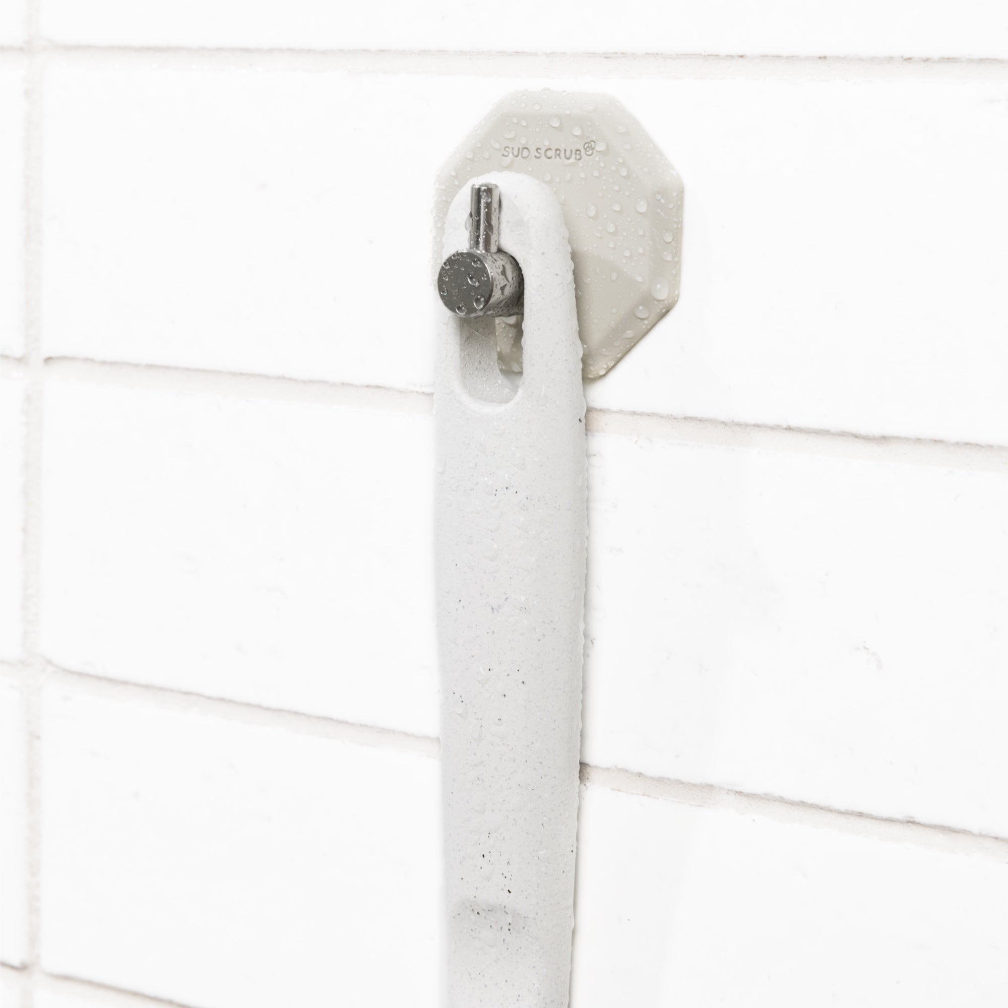 Bottom of Sud Scrub extender handle handing on clay Sud Scrub Shower hook in shower setting