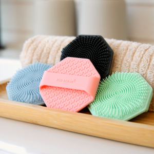 multiple colors of the Sud Scrub face scrubber in a bathroom setting
