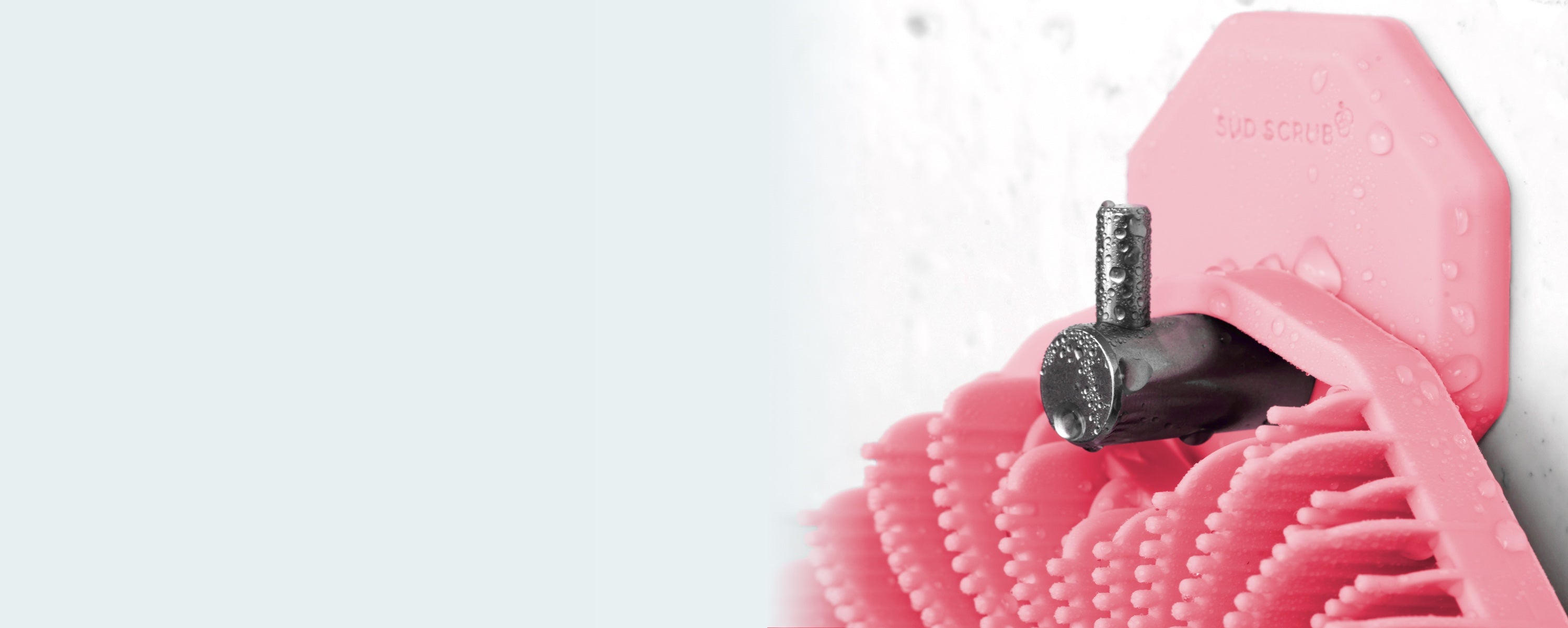 up close shot of pink Sud Scrub Body Scrubber handing on pink Sud Scrub Shower Hook