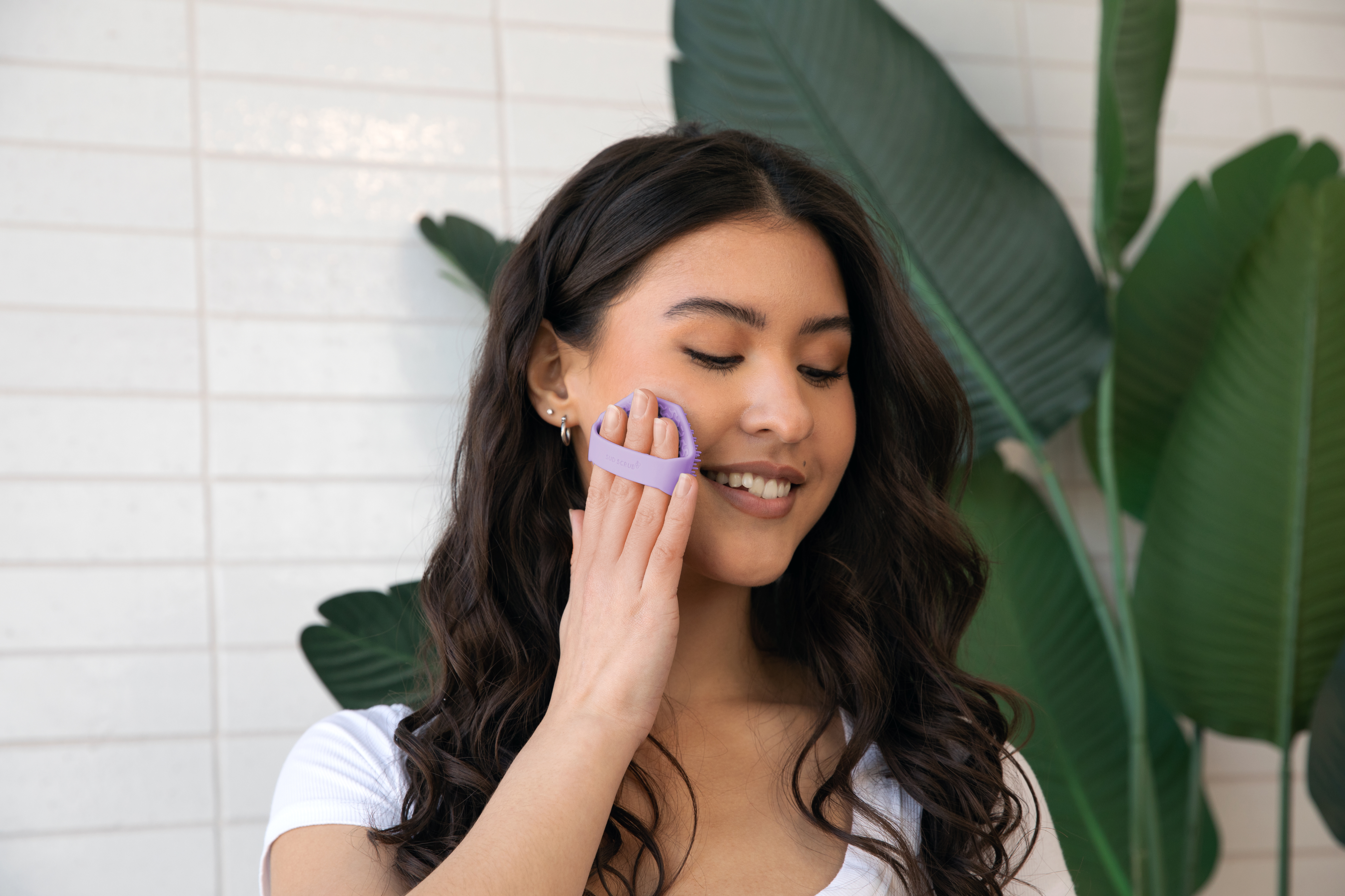 Woman using Sud Scrub face scrubber on her face in the bathroom